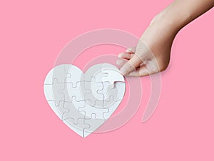 Close up shot hand of woman playing heart shape jigsaw puzzle on