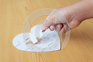 Close up shot hand of woman playing jigsaw puzzle on wooden table