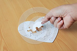 Close up shot hand of woman playing jigsaw puzzle on wooden tabl