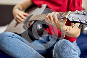 Close up shot of hand of young woman in casual clothes playing guitar