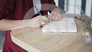 Close up shot of hands of Beautiful and young successful business woman with notepad in a cafe, working as a freelancer
