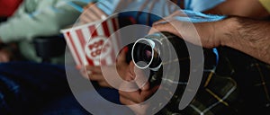 Close up shot of hands of a guy hiding his video camera while recording a pirated movie at the cinema