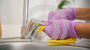 Close-up shot of hands in latex gloves polishing faucet