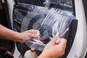 Close up shot hands of man removing old car window film focus on