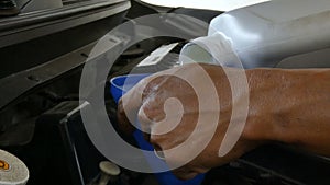 Close up shot hands of mechanic pour filling engine lubricant oil in to car engine