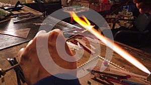 Close-up Shot of Hands Shaping Glass Bead Holding it Over a Gas Torch in a Workshop