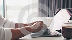 Close up shot of hands of unrecognizable businessman typing on laptop keyboard while working at home office desk