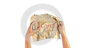 Close-up shot of hands unwrap the crumpled kraft paper that written Love word, Isolated on white background. Emotional and express
