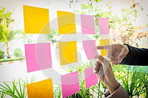 Close up shot of hands of woman sticking adhesive notes on glass