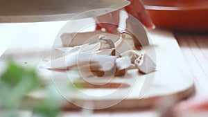 Close up shot hands of woman using kitchen knife slide cut Eringi mushroom on wooden cutting board preparing for cooking