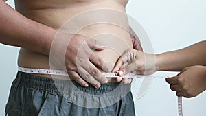 Close up shot hands of women use measure tape around waistline of the fat man