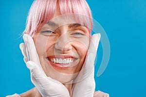 Close up shot of happy smiling woman. Hands of beautician examining female face before giving facial botox injections