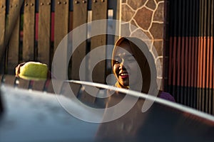 Close up shot hijab woman washing car roof with a smile