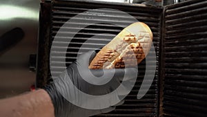 Close-up shot of hot dog bun laying on grate of an electric grill, process of cooking hot dogs in fast food cafe
