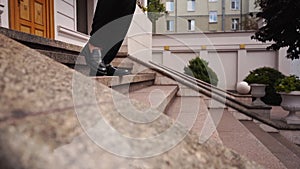 Close up shot of hurry businessman in black formal suit feet in loafer's shoes walking down marble stairs of luxury