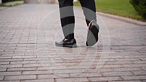 Close up shot of hurry businessman in black formal suit feet in loafer's shoes walking down marble stairs of luxury