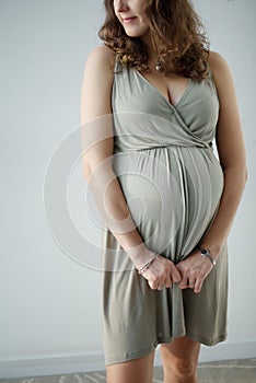 Close up shot of the impersonal pregnant woman with big tummy. Waiting for the baby. Motherhood.