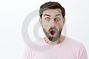 Close-up shot of impressed and shocked stunned caucasian guy with beard dropping jaw from amazement popping eyes at