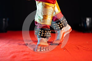 Close up shot of indian bharatanatyam dancer feet with ghungroo kathak or musical anklet dancing on stage - concept of photo