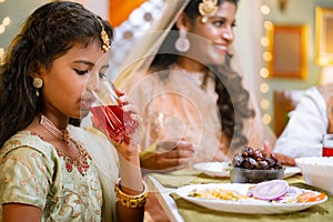 Close up shot of indian girl kid drinking rose soft drinks during ramadan iftar dinner at home - concept of religious