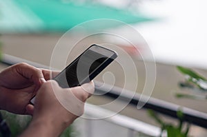 Close up shot of indian male messaging on a touchscreen mobile phone with a foggy background behind him