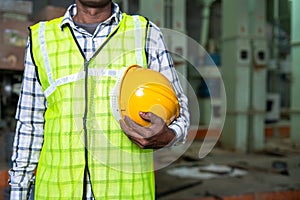 Close up shot of industrial worker standing by holding safety helmet at factory - concept of work ware, safety measures