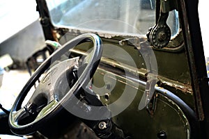 Close up shot inside an old car of the driving wheel, front glass, day light