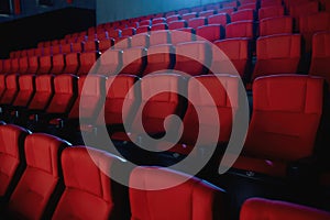 Close up shot of interior of cinema auditorium with lines of red chairs