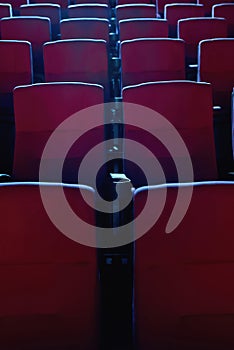 Close up shot of interior of cinema auditorium with lines of red chairs in front of a big screen