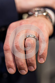 Close-up shot in a jewelry boutique man& x27;s hand adorned with a wedding ring and a blurred expensive watch. Focus