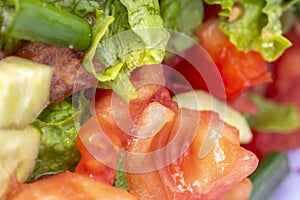 Close-up shot of juicy assorted salad consisting of green salad leaves, tomato, paprika and cucumber