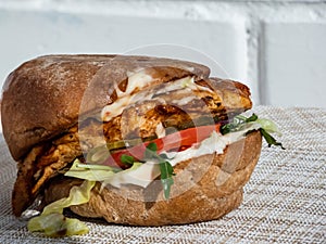 Close-up shot of juicy chicken burger with grilled chicken fillet, ciabata, burger sauce, arugula, pesto, balsamic, salad, pickle