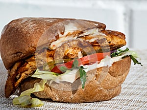 Close-up shot of juicy chicken burger with grilled chicken fillet, ciabata, burger sauce, arugula, pesto, balsamic, salad, pickle