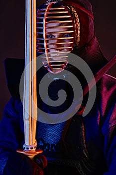 Close up shot, Kendo fighter wearing in an armor, traditional kimono, helmet practicing martial art with shinai bamboo