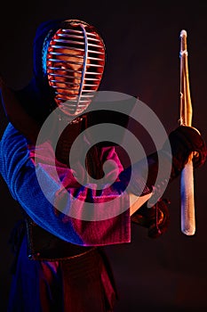 Close up shot, Kendo fighter wearing in an armor, traditional kimono, helmet practicing martial art with shinai bamboo