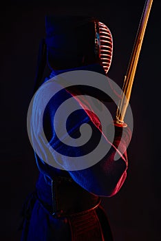 Close up shot, Kendo fighter wearing in an armor, traditional kimono, helmet practicing martial art with shinai bamboo