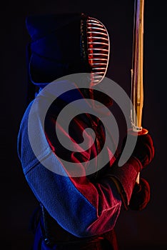 Close up shot, Kendo fighter wearing in an armor, traditional kimono, helmet practicing martial art with shinai bamboo