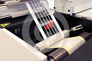 Close-up shot of labels manufacturing on flexo printing machine. Photo detail of matrix waste or trim removal from adhesive.
