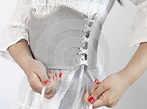 close-up shot of a lady dressed in a white dress with a wide grey leather belt or corset