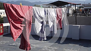 A close up shot of laundry drying outside under sun. Shirts hanging on a wire on the roof. Dehradun City, Uttarakhand India