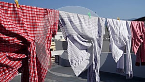A close up shot of laundry drying outside under sun. Shirts hanging on a wire on the roof. Dehradun City, Uttarakhand India