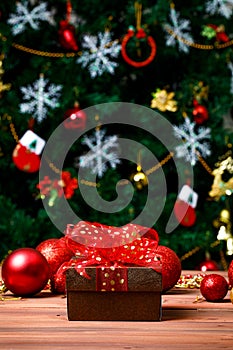 Close up shot of leather gift present box wrapped with gold dot on red ribbon bow tie placed on dark wooden table in front glossy