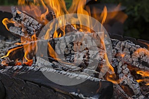 Close up shot of log pieces and fire wood, charcoal and ashes  burning in hot oranges flames in an old vintage brazier