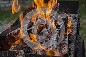 Close up shot of log pieces and fire wood, charcoal and ashes  burning in hot oranges flames in an old vintage brazier