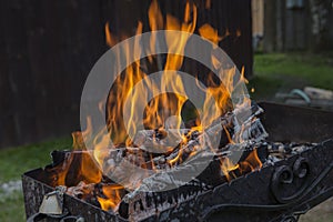 Close up shot of log pieces and fire wood, charcoal and ashes  burning in hot oranges flames in an old vintage brazier