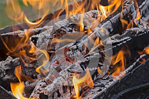 Close up shot of log pieces and fire wood, charcoal and ashes  burning in hot oranges flames in an old vintage brazier