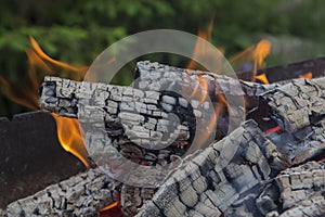 Close up shot of log pieces and fire wood, charcoal and ashes  burning in hot oranges flames in an old vintage brazier