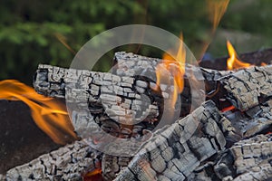 Close up shot of log pieces and fire wood, charcoal and ashes  burning in hot oranges flames in an old vintage brazier