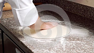 Close-up shot of male chef hands rolling out pizza dough in kitchen