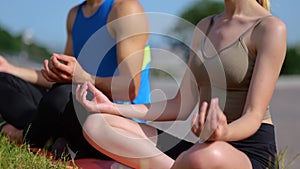 Close up shot of male and female meditating practicing yoga outdoors. Caucasian man and woman sitting on grass during